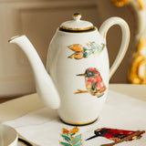 Decorative teapot with bird and floral designs on a table.