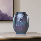 A blue and purple iridescent textured ceramic vase displayed on a light marble-top cabinet in a modern interior setting.