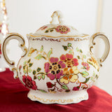 Decorative ceramic sugar bowl with floral patterns on a red surface
