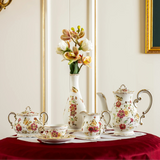 Coffee set on a red tablecloth with a decorative wall mirror and floral arrangement in the background.