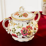 Decorative ceramic sugar bowl with floral patterns on a red surface