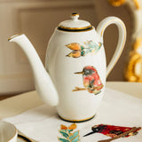 Decorative teapot with bird and floral designs on a table.
