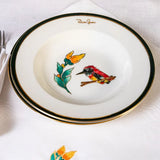 Dinner setting with decorative plates featuring bird designs on a white tablecloth.