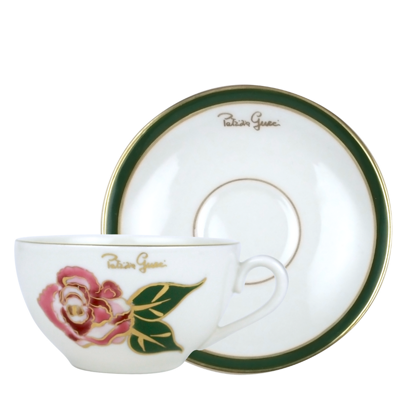 A white porcelain coffee cup with a pink and green floral design and the Patrizia Gucci brand name on the side, accompanied by a matching saucer.