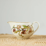 Decorative ceramic creamer with floral patterns on a woven surface