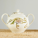 Ceramic sugar pot with floral design on a textured surface