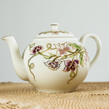 Ceramic teapot with floral designs on a textured surface