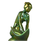 Gold-colored sculpture of a mermaid figure on a white background