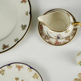 Decorative ceramic plates and a cream pitcher with floral patterns on a white background