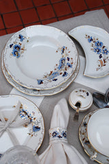 Zsolnay Cornflower dinner set featuring hand-painted blue floral plates and 24K gold accents.