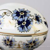 Close up photo to Zsolnay Cornflower porcelain round bonbonnier featuring hand-painted blue flowers and 18K gold details 